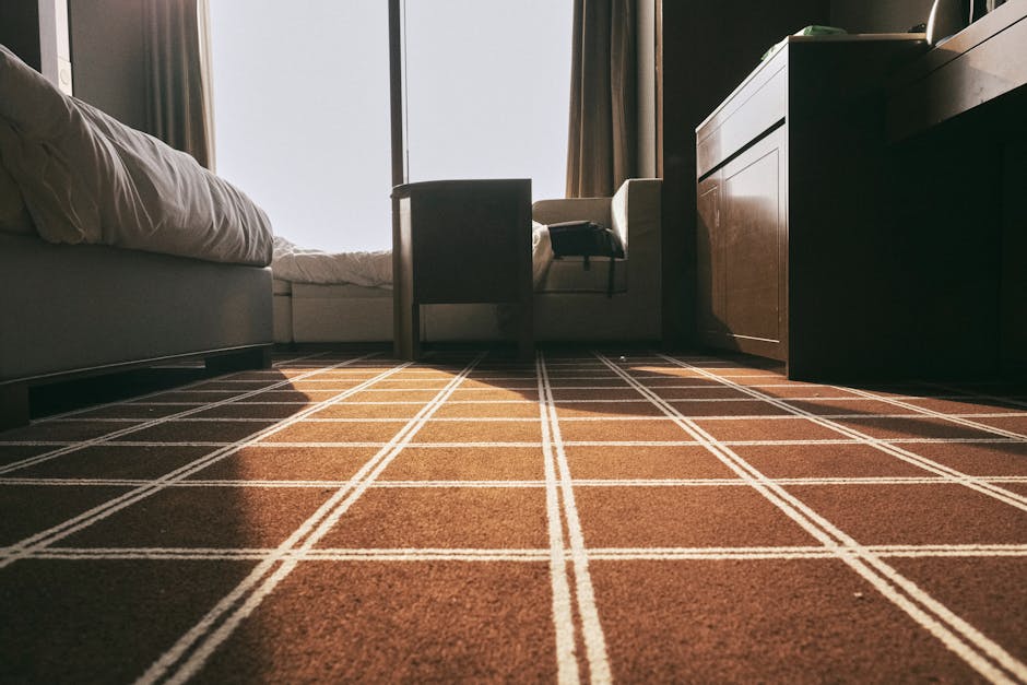 Low-angle view of a clean, textured carpet running through a corridor in a residential or commercial building. The carpet has a uniform, plush surface with no visible stains or debris, indicating rece